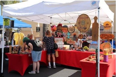 3rd Saturday Market in the Park. Patrons shopping a vendor's tent with mixed goods.