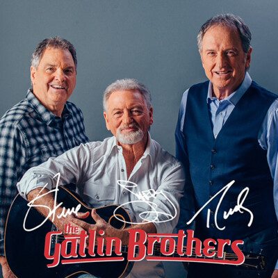Three men posing for photo with guitar.