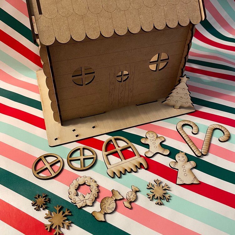Wooden gingerbread house with wood pieces on a striped wrapping paper background