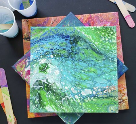 Photo of canvases that have acrylic paint poured on them.