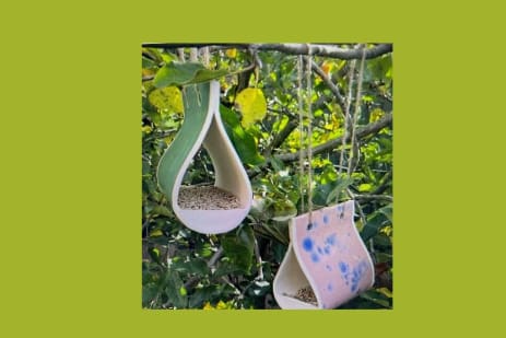 Photo of handmade birdfeeders on a green background.