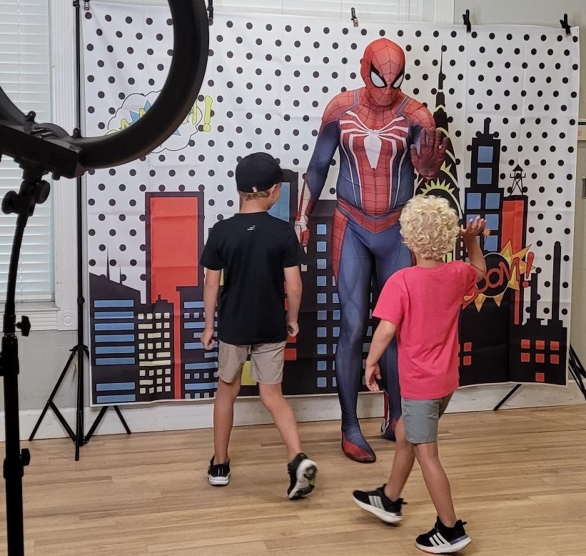 Photo of two boys next to a person dressed as Spiderman.
