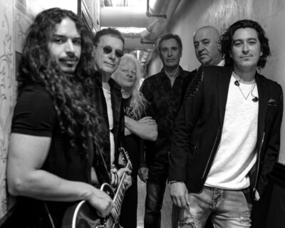 Black and white photo of bandmates standing in a hallway.