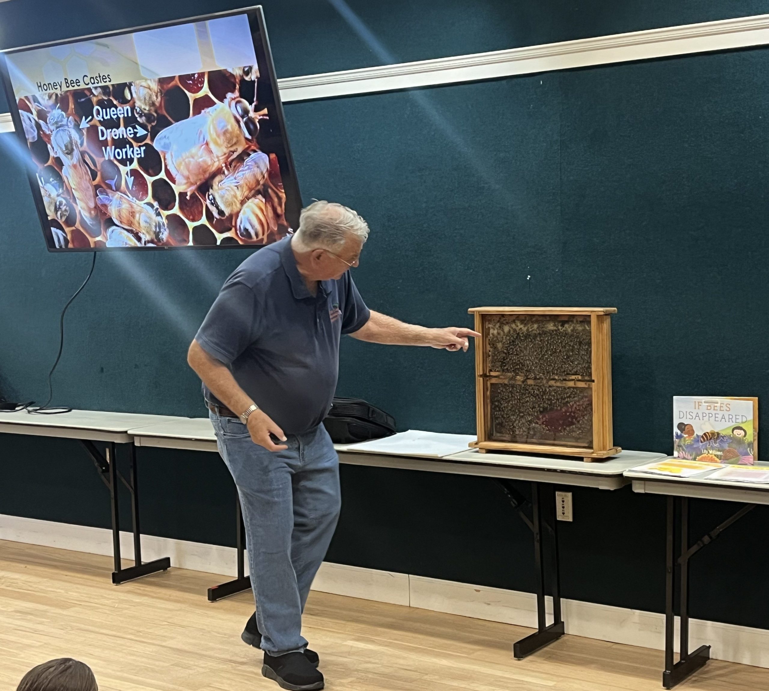 Photo of a man presenting a bee enclosure on a table.