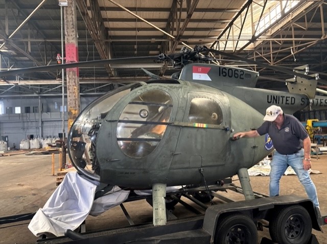 Photo of a man next to a retired military helicopter.