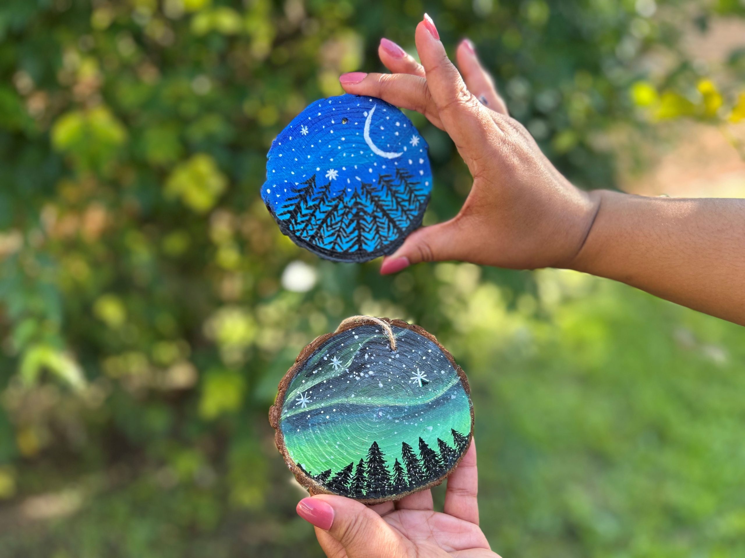 Hands holding painted slices of wood.